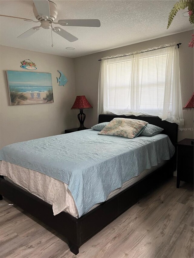 bedroom featuring a textured ceiling, ceiling fan, and wood finished floors