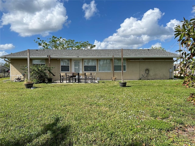 back of house with stucco siding, a patio, and a yard