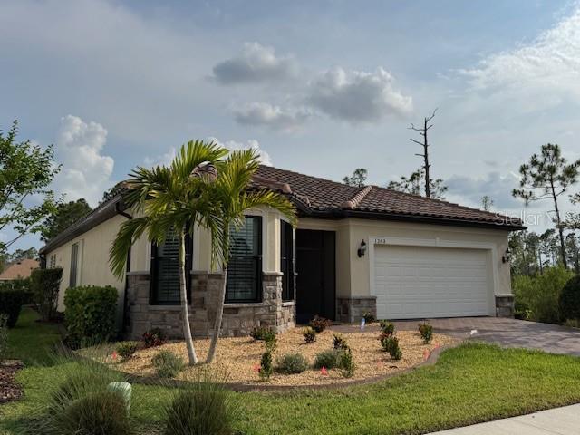 1263 Cicely Ct, North Port, FL 34289 - view of front facade featuring stucco siding, an attached garage, stone siding, and driveway