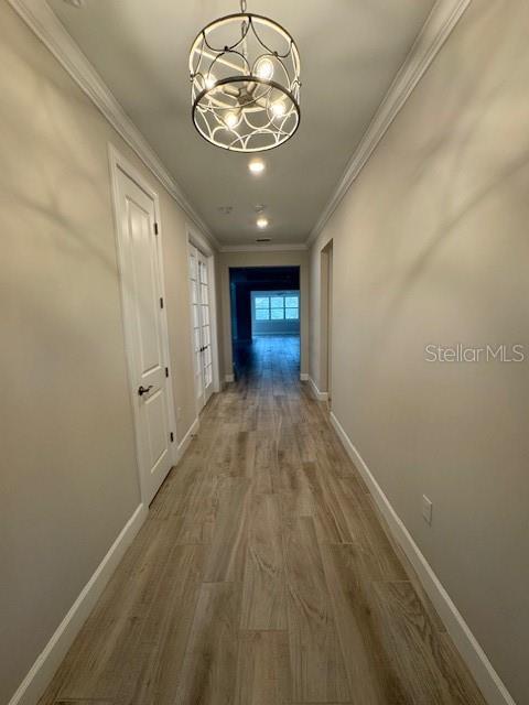 1263 Cicely Ct, North Port, FL 34289 - hall featuring crown molding, baseboards, wood finished floors, and a chandelier