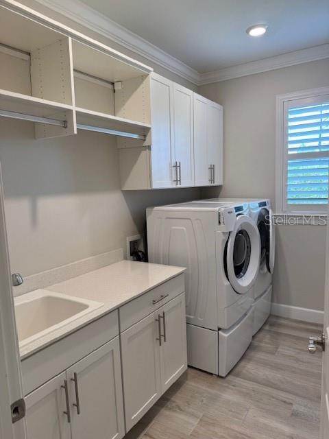1263 Cicely Ct, North Port, FL 34289 - laundry area featuring separate washer and dryer, cabinet space, ornamental molding, light wood finished floors, and baseboards