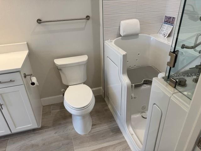 1263 Cicely Ct, North Port, FL 34289 - full bath with baseboards, vanity, wood finished floors, a jetted tub, and toilet