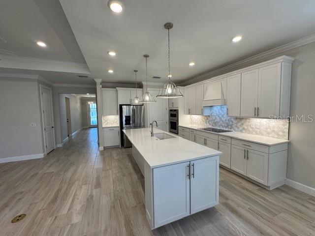 1263 Cicely Ct, North Port, FL 34289 - kitchen with crown molding, baseboards, appliances with stainless steel finishes, premium range hood, and light wood-style flooring