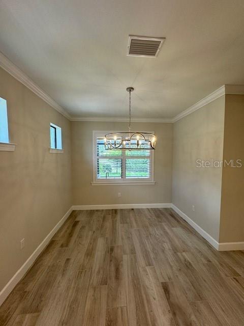 1263 Cicely Ct, North Port, FL 34289 - unfurnished dining area with wood finished floors, a chandelier, baseboards, and crown molding