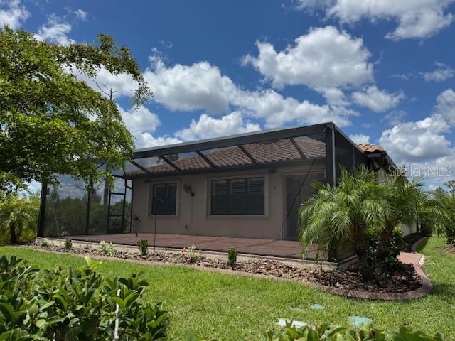 1263 Cicely Ct, North Port, FL 34289 - rear view of house with glass enclosure, a patio, a lawn, and stucco siding