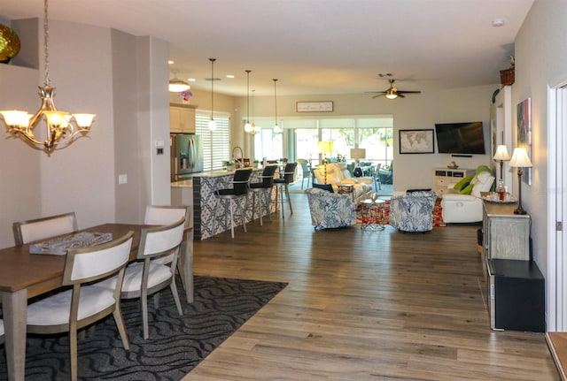 dining room with ceiling fan with notable chandelier, plenty of natural light, recessed lighting, and dark wood finished floors