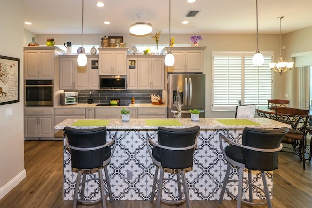 kitchen with stainless steel appliances, a kitchen breakfast bar, visible vents, and an island with sink