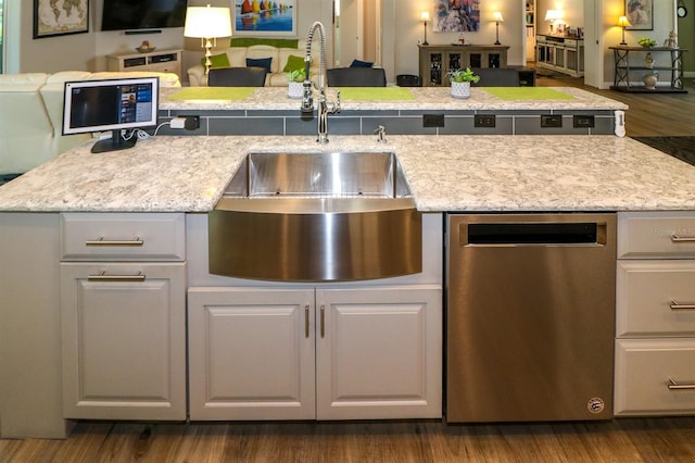 kitchen with a sink, dark wood-style flooring, open floor plan, light stone countertops, and dishwasher