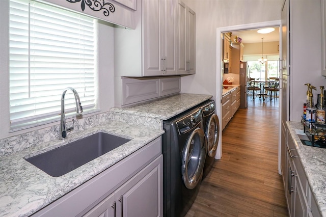 laundry area with a chandelier, wood finished floors, a sink, independent washer and dryer, and cabinet space