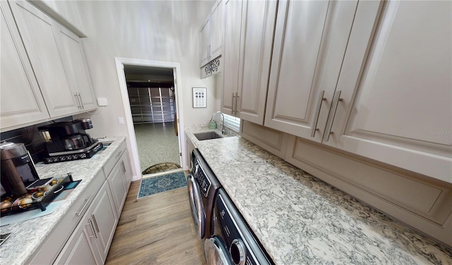 kitchen with light wood finished floors, white cabinetry, and a sink