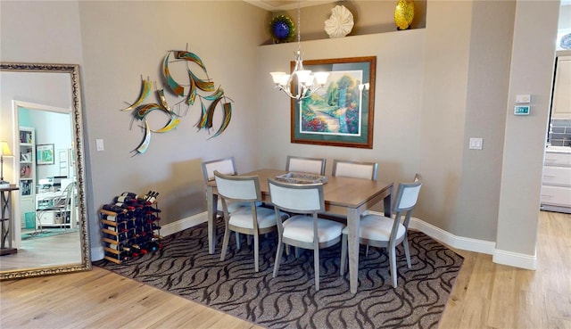 dining room with wood finished floors, baseboards, and an inviting chandelier