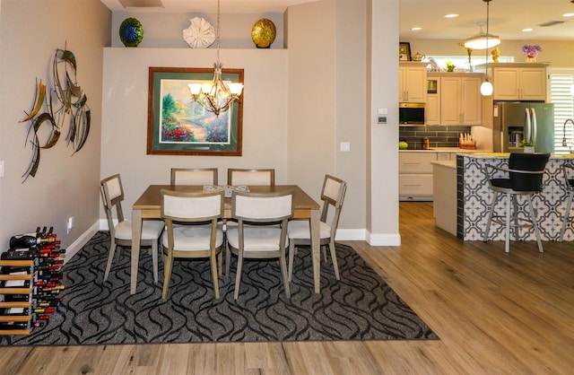 dining area featuring a chandelier, wood finished floors, visible vents, and baseboards