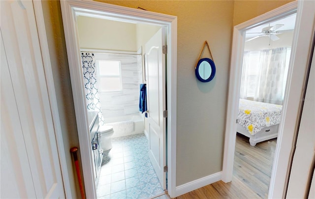 full bath featuring shower / bathtub combination, wood finished floors, toilet, baseboards, and ceiling fan
