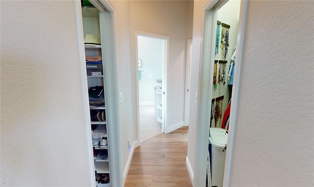 hallway with light wood-type flooring and a textured wall