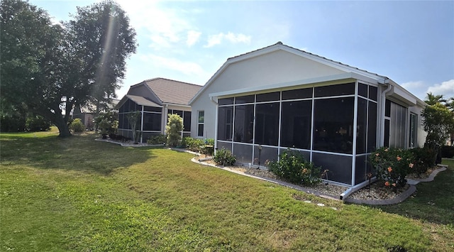 back of house with a lawn, a sunroom, and stucco siding