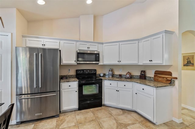 kitchen with stainless steel appliances, recessed lighting, white cabinetry, and dark stone countertops