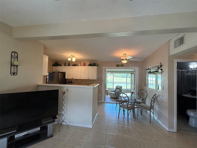 123 Poinsettia Cir NE, Port Charlotte, FL 33952 - kitchen with light tile patterned flooring, freestanding refrigerator, baseboards, a peninsula, and lofted ceiling