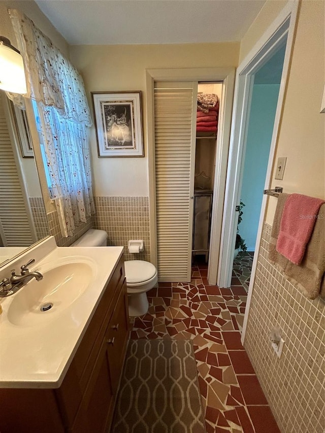 123 Poinsettia Cir NE, Port Charlotte, FL 33952 - bathroom with a wainscoted wall, toilet, a closet, tile walls, and vanity
