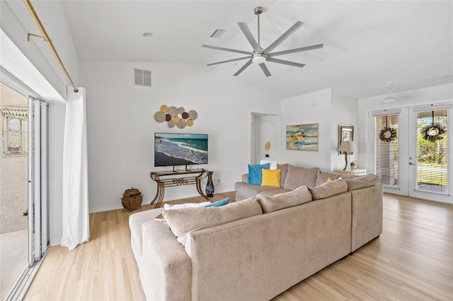 living room featuring light wood-type flooring, high vaulted ceiling, ceiling fan, and visible vents