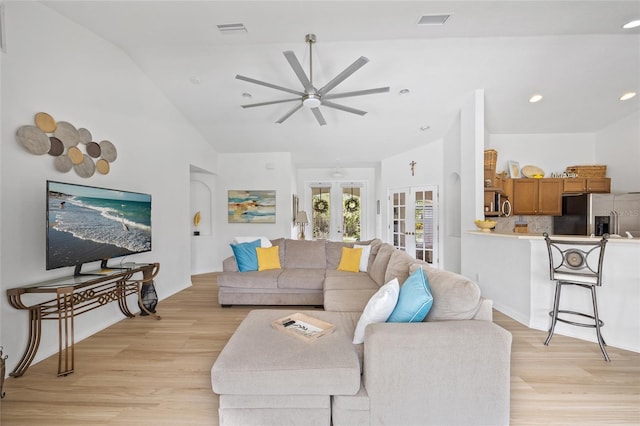 living area with visible vents, ceiling fan, light wood-type flooring, vaulted ceiling, and french doors