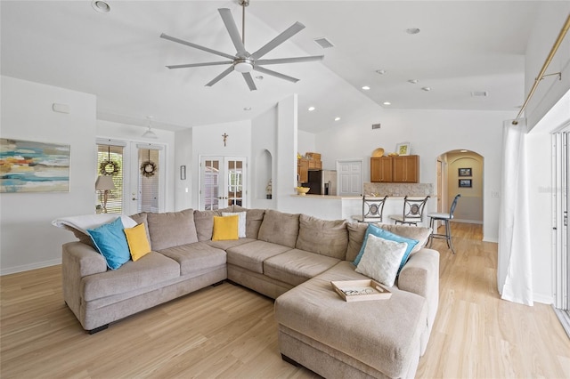 living area featuring baseboards, visible vents, ceiling fan, arched walkways, and light wood finished floors