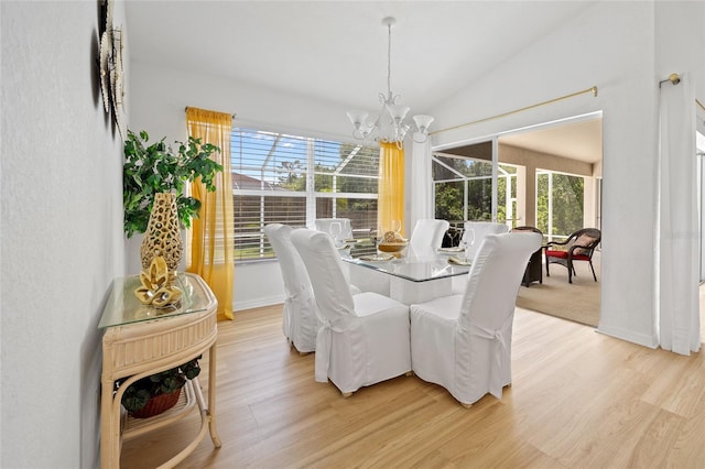 dining space with light wood finished floors, a notable chandelier, baseboards, and lofted ceiling