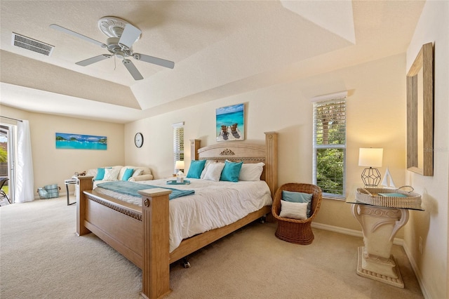 carpeted bedroom featuring access to outside, visible vents, a raised ceiling, and a ceiling fan