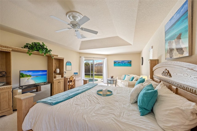 bedroom featuring a ceiling fan, a textured ceiling, a tray ceiling, access to exterior, and light carpet