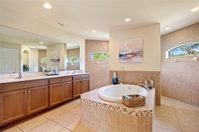 full bathroom featuring double vanity, tile patterned floors, a walk in shower, a bath, and a sink