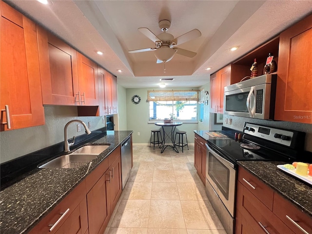 931 Juno Dr, Punta Gorda, FL 33950 - kitchen featuring stainless steel appliances, a raised ceiling, brown cabinetry, dark stone countertops, and recessed lighting