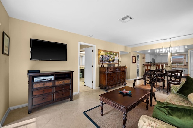 living area with light tile patterned flooring, a notable chandelier, baseboards, and visible vents
