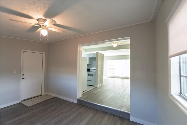 empty room with a textured ceiling, baseboards, ceiling fan, and wood finished floors