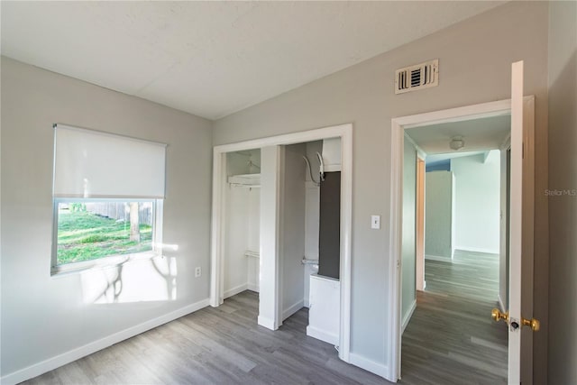 unfurnished bedroom with lofted ceiling, baseboards, dark wood-style floors, visible vents, and a closet