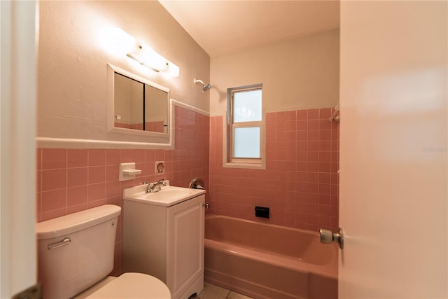 full bath featuring tile walls, tub / shower combination, toilet, vanity, and wainscoting