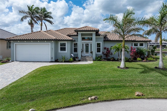 mediterranean / spanish home featuring a front lawn, decorative driveway, stucco siding, and an attached garage