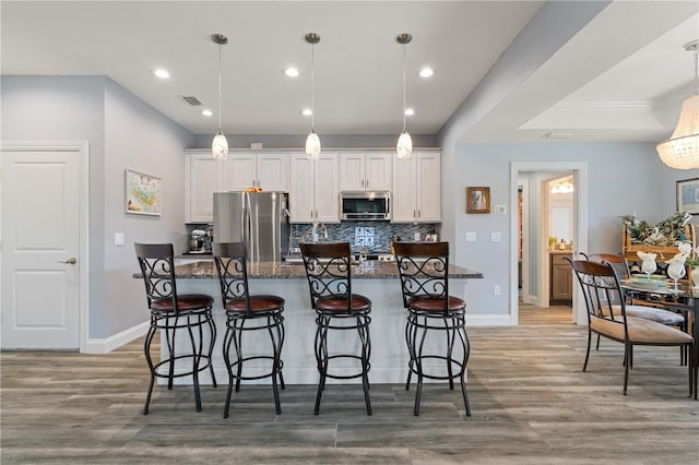 kitchen featuring white cabinetry, stainless steel appliances, a breakfast bar area, and visible vents