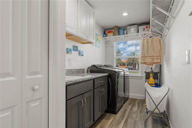 laundry room with baseboards, wood finished floors, a sink, washer and dryer, and cabinet space
