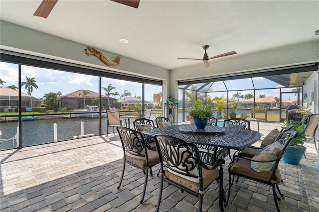 sunroom / solarium with a water view, ceiling fan, outdoor dining space, and a residential view