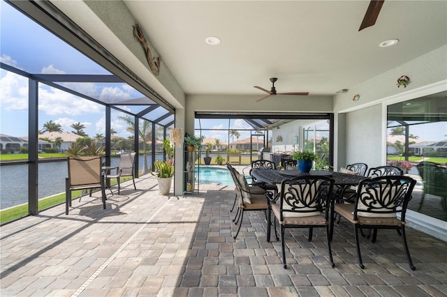 sunroom / solarium with a ceiling fan, a water view, and outdoor dining space