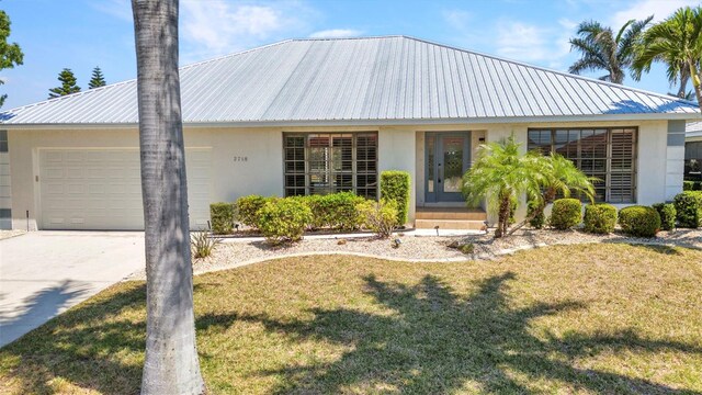 2718 Saint Thomas Dr, Punta Gorda, FL 33950 - view of front facade with a garage, a front lawn, driveway, metal roof, and stucco siding