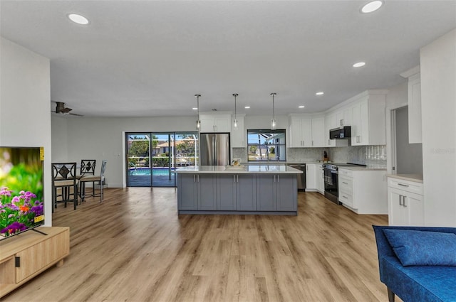 2718 Saint Thomas Dr, Punta Gorda, FL 33950 - kitchen with white cabinets, stainless steel appliances, a center island, open floor plan, and light countertops