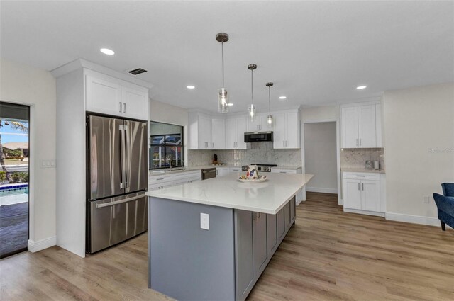 2718 Saint Thomas Dr, Punta Gorda, FL 33950 - kitchen featuring decorative backsplash, white cabinetry, light wood-style flooring, appliances with stainless steel finishes, and a kitchen island