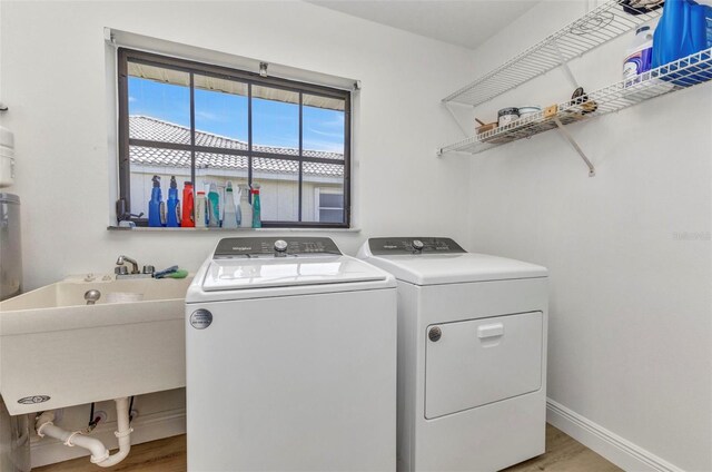 2718 Saint Thomas Dr, Punta Gorda, FL 33950 - clothes washing area with laundry area, a sink, washing machine and dryer, baseboards, and light wood-style flooring