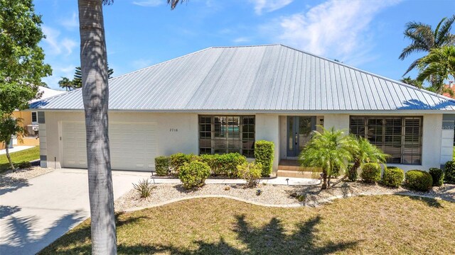 2718 Saint Thomas Dr, Punta Gorda, FL 33950 - view of front of property with metal roof, a front lawn, concrete driveway, stucco siding, and a garage