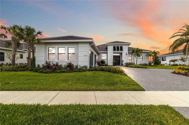 view of front facade featuring stucco siding, decorative driveway, a garage, and a front lawn