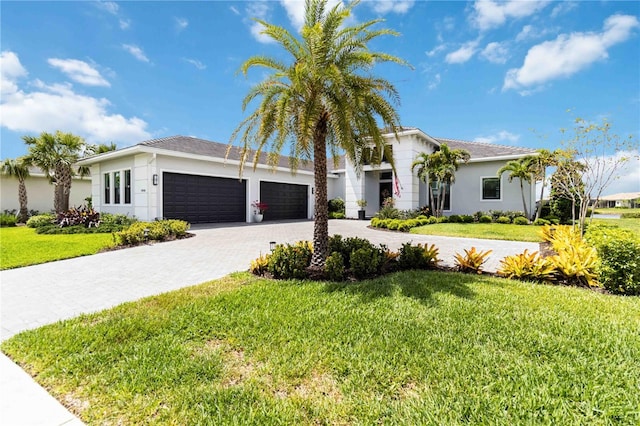 view of front of property with a front yard, decorative driveway, stucco siding, and an attached garage