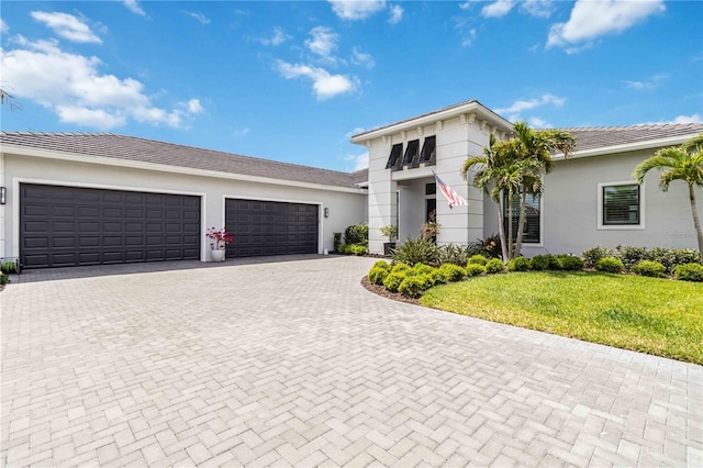 view of front of property with a front lawn, decorative driveway, stucco siding, and a garage