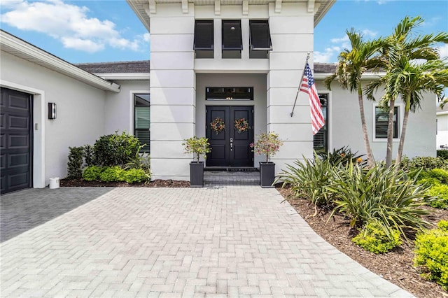 view of exterior entry with stucco siding and an attached garage