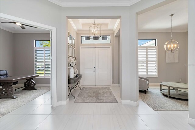 foyer entrance with tile patterned flooring, ornamental molding, and a chandelier
