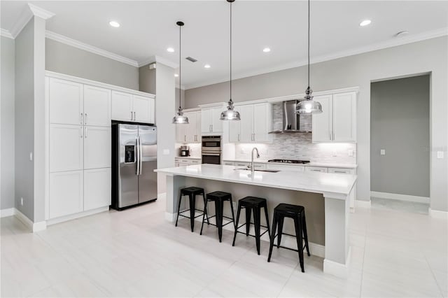 kitchen featuring a sink, a breakfast bar area, stainless steel appliances, wall chimney range hood, and white cabinets
